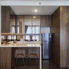 Modern kitchen with bar stools, stainless steel refrigerator, and ample storage