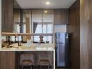 Modern kitchen with bar stools, stainless steel refrigerator, and ample storage