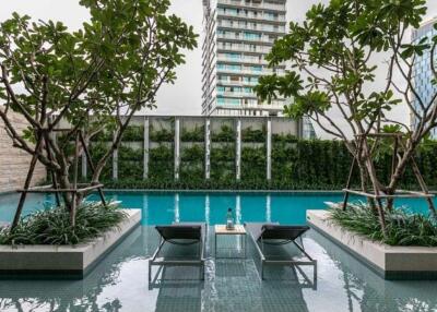 Outdoor swimming pool with lounge chairs and greenery