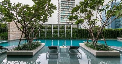 Outdoor swimming pool with lounge chairs and greenery