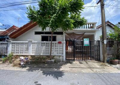 Front view of single-story house with a tree and gate