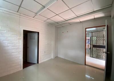 Spacious main living area with tiled floor, textured white walls, and doorways leading to other rooms.