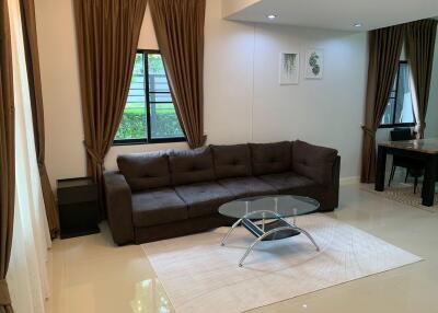 Bright living room with brown curtains, a dark brown sofa, and glass coffee table