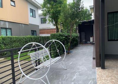 Outdoor patio area with metal bench and greenery