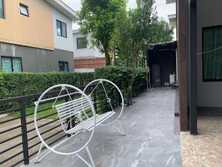 Outdoor patio area with metal bench and greenery