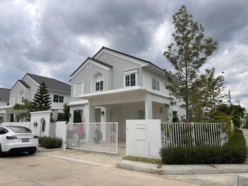 Front view of a modern white house with a car parked in front and greenery