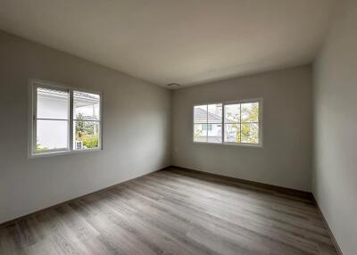 Empty bedroom with large windows and wood flooring