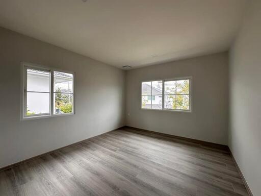 Empty bedroom with large windows and wood flooring