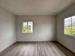 Spacious empty bedroom with large windows and wooden floor