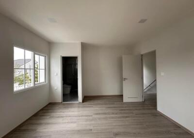 Spacious empty bedroom with large window and door leading to en-suite bathroom