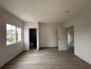 Spacious empty bedroom with large window and door leading to en-suite bathroom