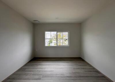 Spacious empty bedroom with wooden flooring and a large window