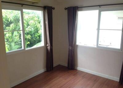 Bright bedroom with two windows and wooden flooring