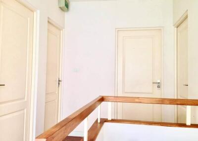 A bright hallway with multiple doors and a wooden railing