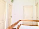 A bright hallway with multiple doors and a wooden railing