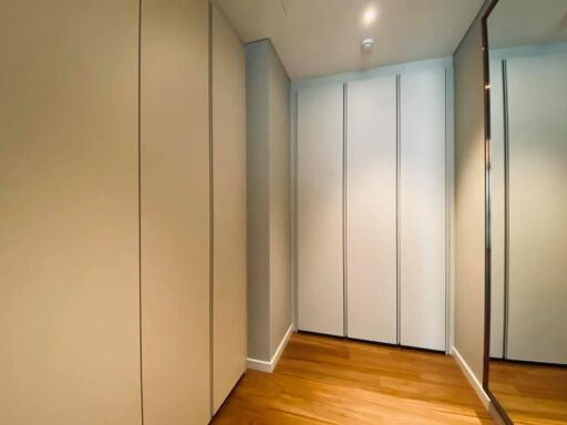 Modern walk-in closet with wooden flooring and ample storage space