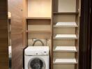 Laundry area with a washing machine and storage shelves