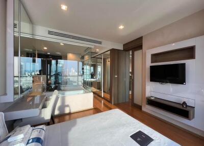 Modern bedroom with city view, glass walls, and TV