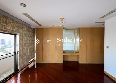 Spacious bedroom with large windows and built-in wooden wardrobes