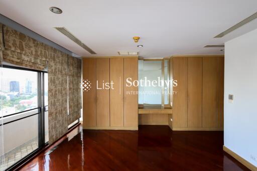 Spacious bedroom with large windows and built-in wooden wardrobes