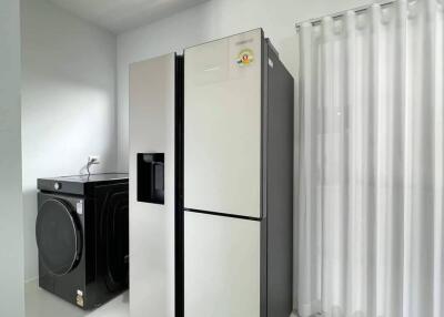 Laundry room with modern washing machine and a large refrigerator