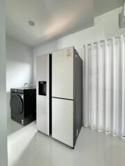 Laundry room with modern washing machine and a large refrigerator