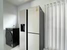 Laundry room with modern washing machine and a large refrigerator