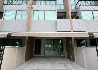 Front view of a multi-story residential building with large windows and balcony