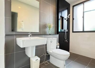 Modern bathroom with grey tiles, sink, toilet, and shower