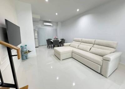 Modern and spacious living room with white sofa and dining area