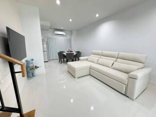 Modern and spacious living room with white sofa and dining area