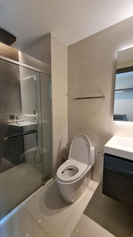 Modern bathroom with glass shower enclosure, toilet, and vanity