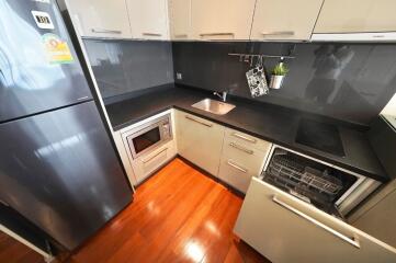 Modern kitchen with wooden flooring, appliances, and sleek cabinetry