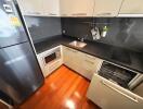 Modern kitchen with wooden flooring, appliances, and sleek cabinetry