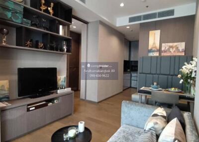 Modern living room with wall-mounted TV, grey couch, coffee table, and decorative shelves