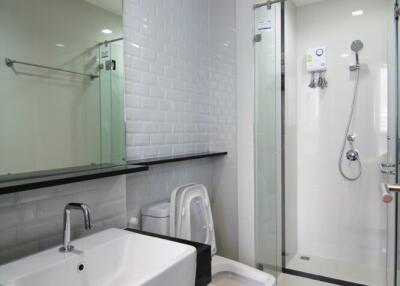 Modern bathroom with white tiles, glass shower, and vanity sink