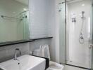 Modern bathroom with white tiles, glass shower, and vanity sink