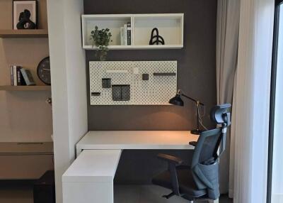 Modern home office with desk, chair, shelving, and natural light