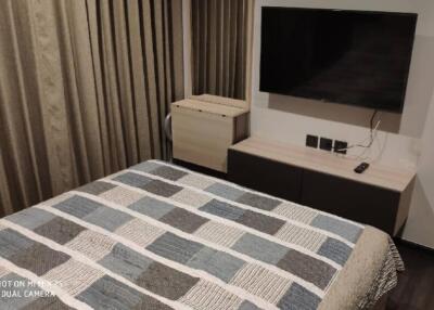 Modern bedroom with a large TV and quilted bedspread