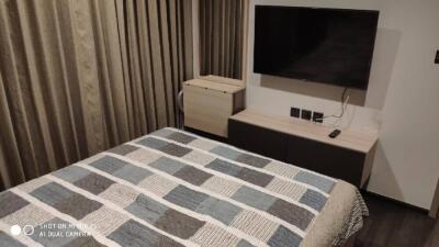 Modern bedroom with a large TV and quilted bedspread