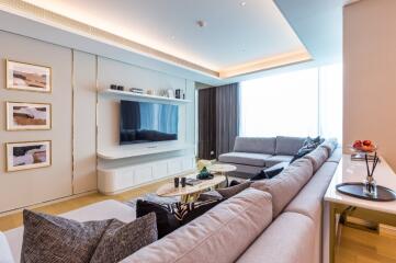 Modern living room with large sectional sofa, wall-mounted TV, and minimalist decor