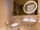 Modern bathroom with a round-lit mirror, sink, and toilet