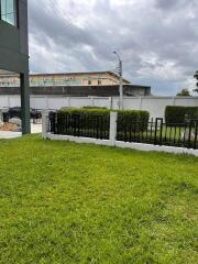 green lawn with fenced border and cloudy sky