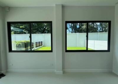 Living room with large windows facing a fenced garden