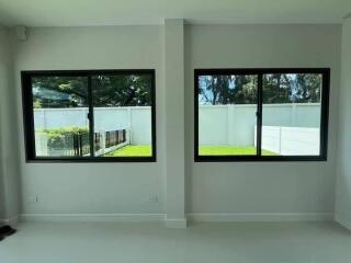 Living room with large windows facing a fenced garden