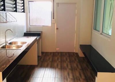 Modern kitchen with open window, stainless steel sink, and wooden floor