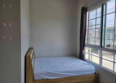 Bedroom with a wooden bed frame and large windows