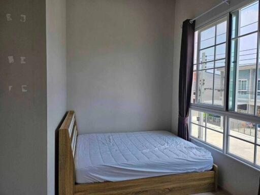 Bedroom with a wooden bed frame and large windows