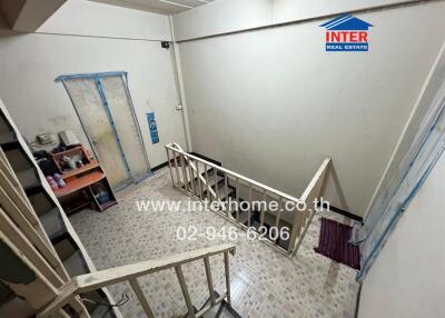 Indoor stairwell area with railing and tiled floor