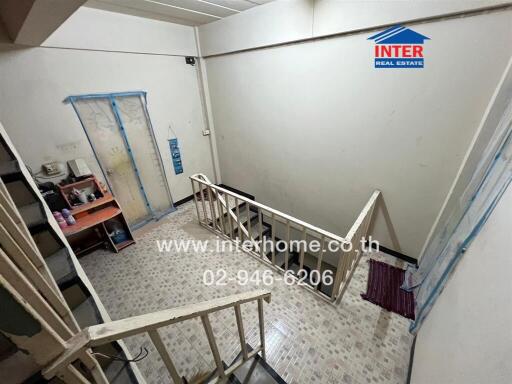 Indoor stairwell area with railing and tiled floor